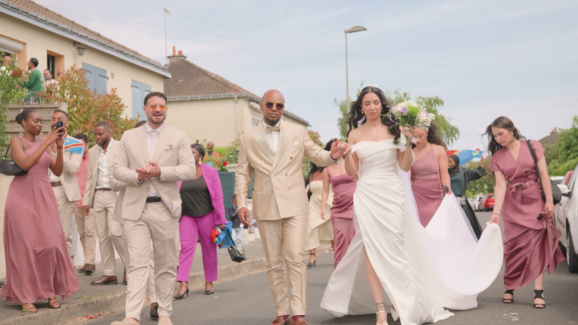 Le cortège des mariés dans la rue avec les invités.